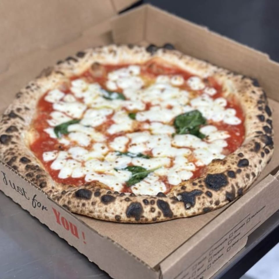 BareBakedPizza's Margherita pizza with fresh mozzarella, basil, and a charred crust in a delivery box.