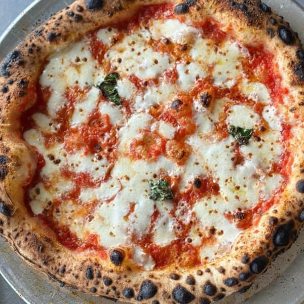 BareBakedPizza's Margherita pizza with melted mozzarella, red sauce, and basil on a charred crust.