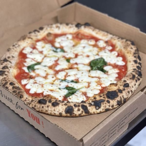 A BareBakedPizza Margherita pizza with fresh mozzarella, tomato sauce, and basil in a cardboard box.
