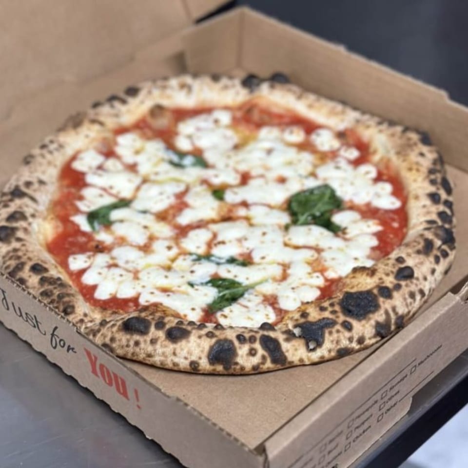 A BareBakedPizza Margherita pizza with fresh mozzarella, tomato sauce, and basil in a cardboard box.