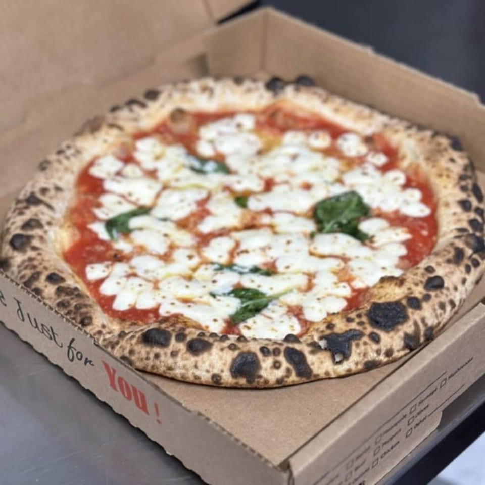 A BareBakedPizza Margherita pizza with fresh mozzarella and basil in a cardboard box.